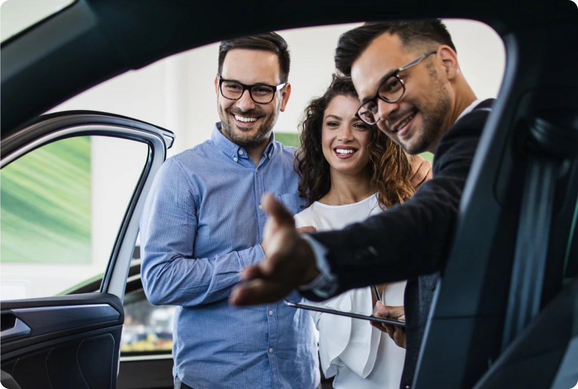 Couple viewing new car with salesman